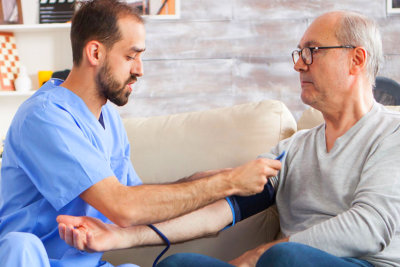 middle aged man checking the blood pressure of an elderly man